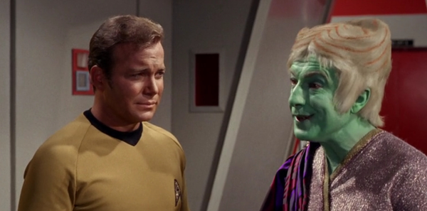 A green man with cinnamon-roll hair speaks to Kirk, who looks bemused.